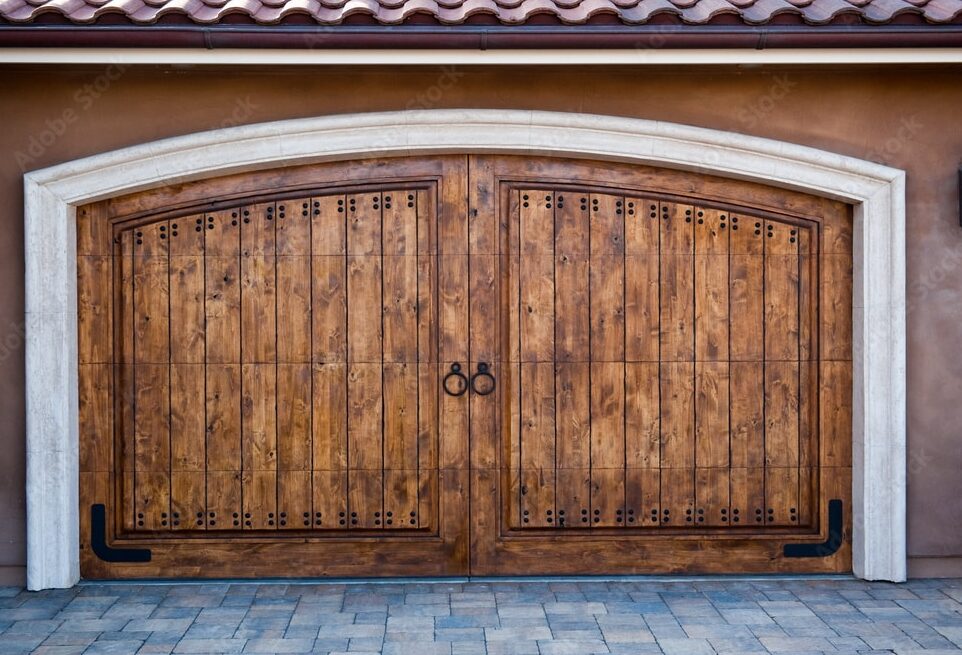 A wooden custom garage door on an old, stylish house.