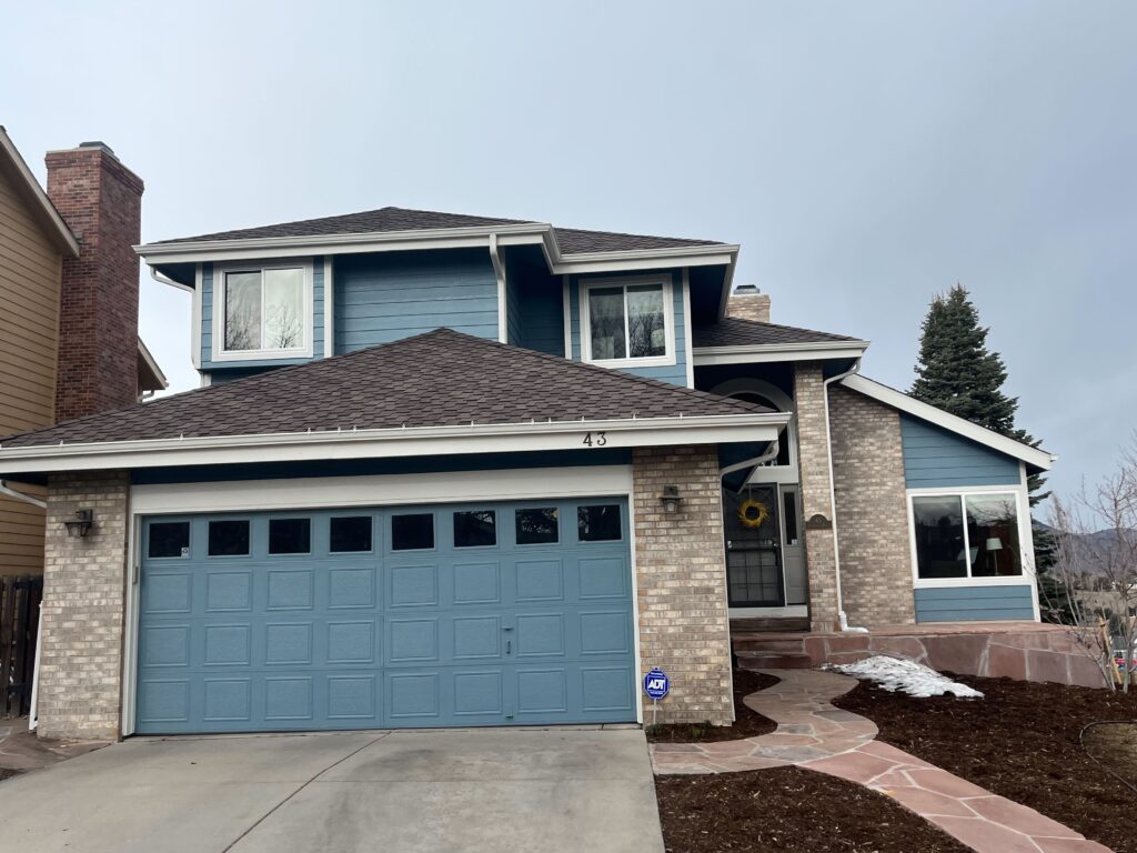 Two story house with blue siding and a matching blue garage door.